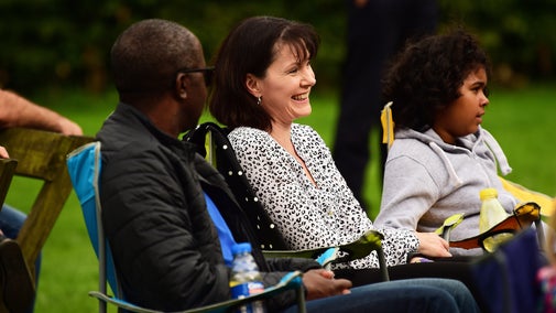 A family of three sitting in camping chairs enjoying a live performance at Cliveden, Buckinghamshire